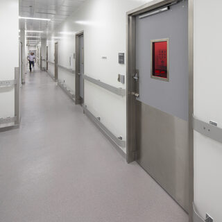 Corridor with a man at the end and closed doors on the right