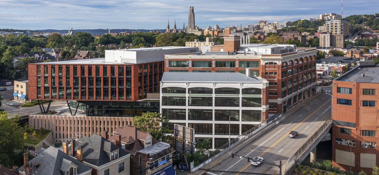 An indutrial-looking building with the Pittsburgh skyline behind it