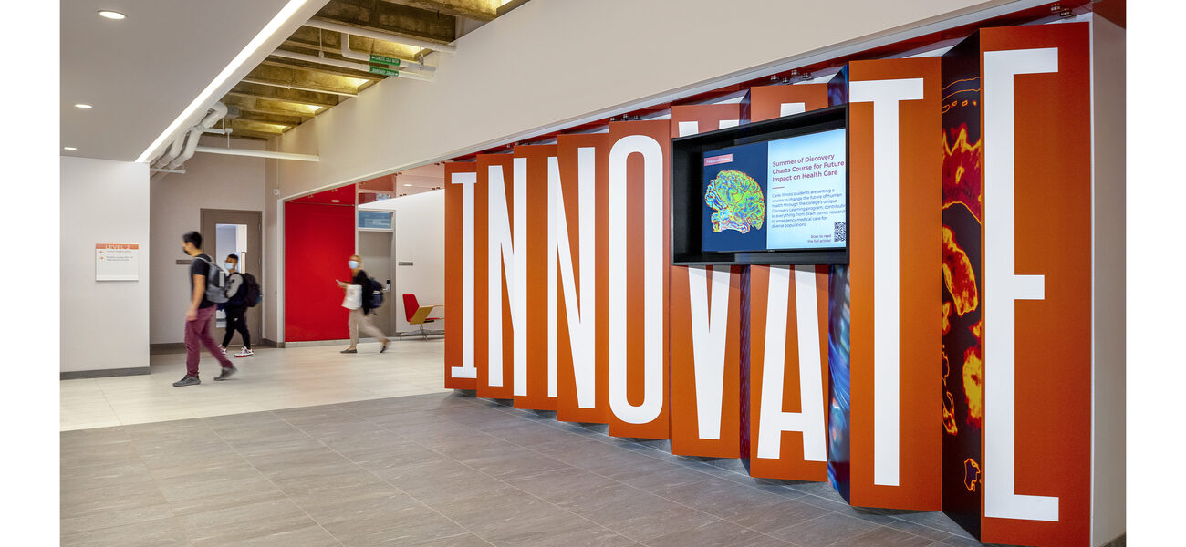 College students walk past a large art installation with the word "Innovate."