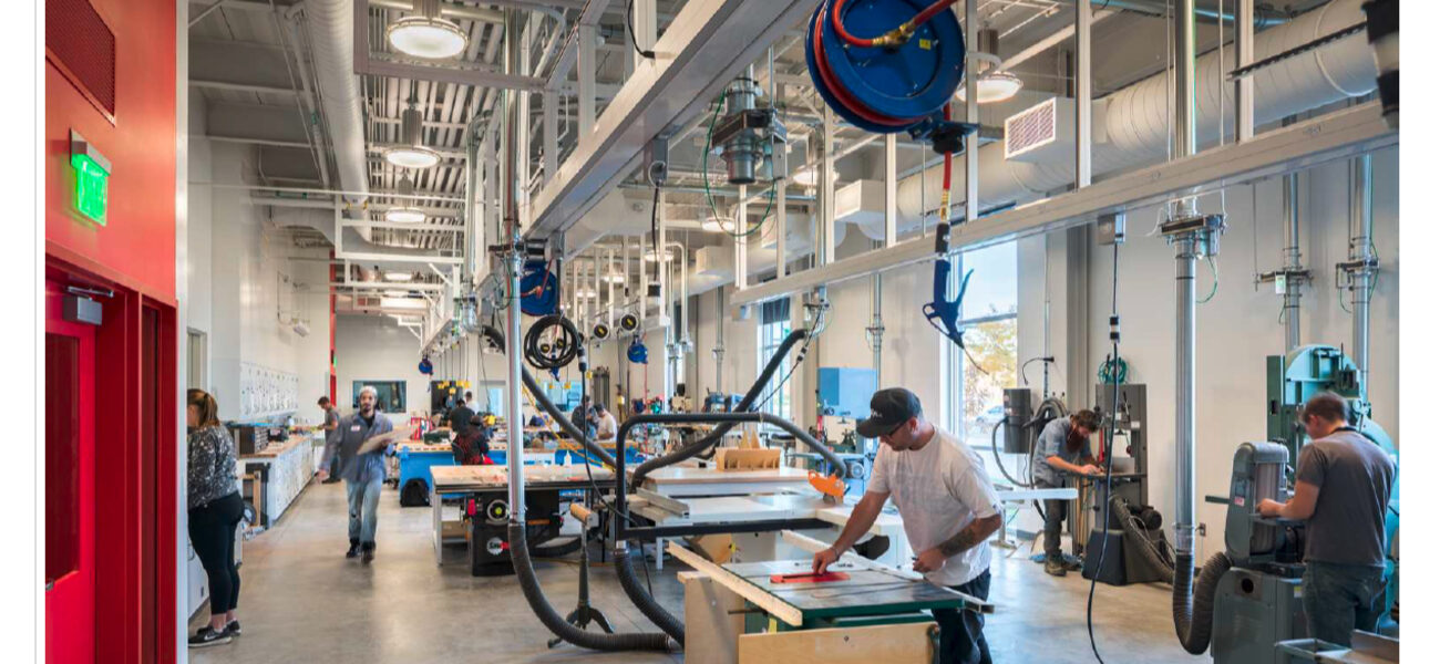College students operate machinery in a large engineering lab.