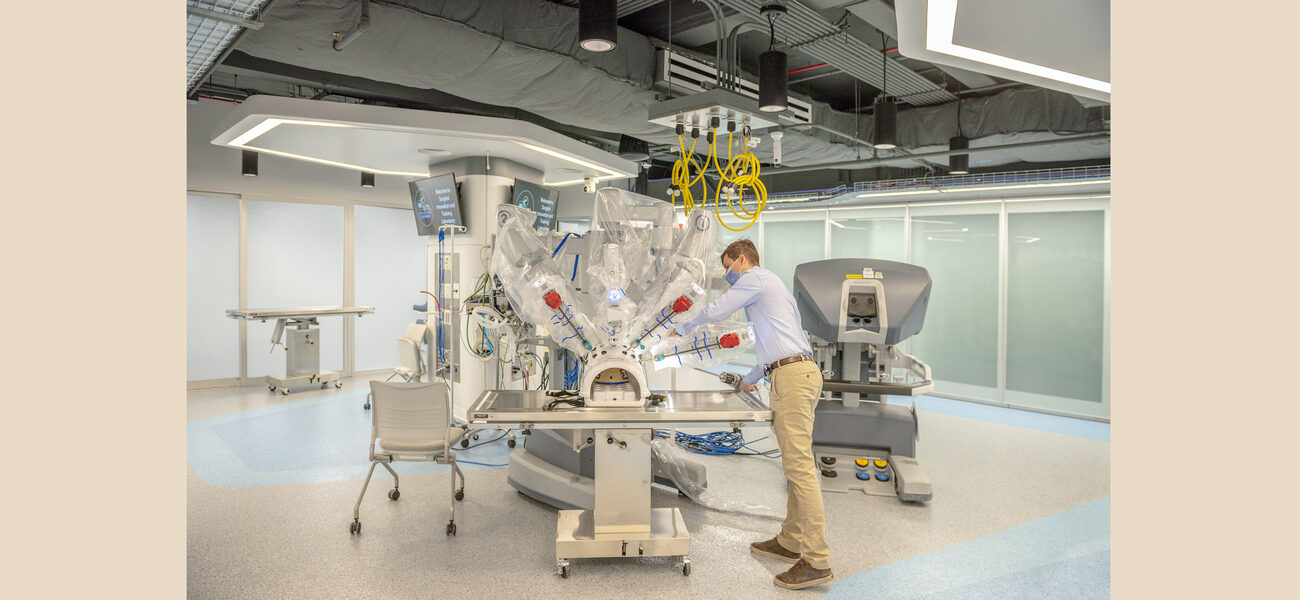 A man works on a large robot attached to an operating table.