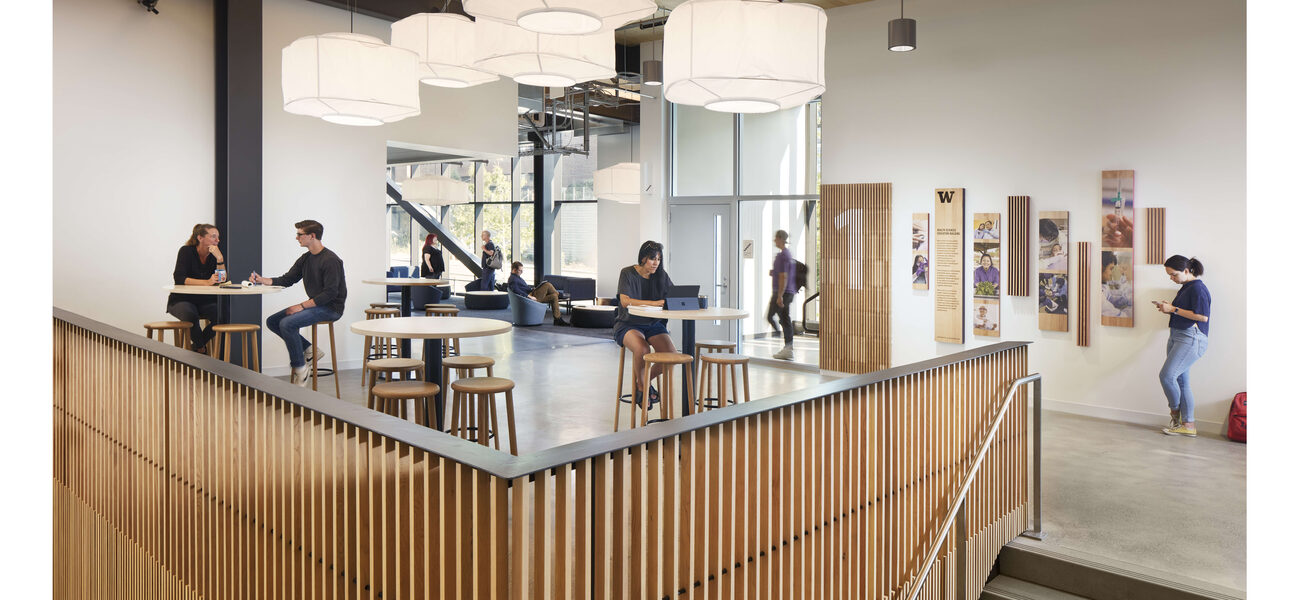 Students work at small tables on a landing near a staircase