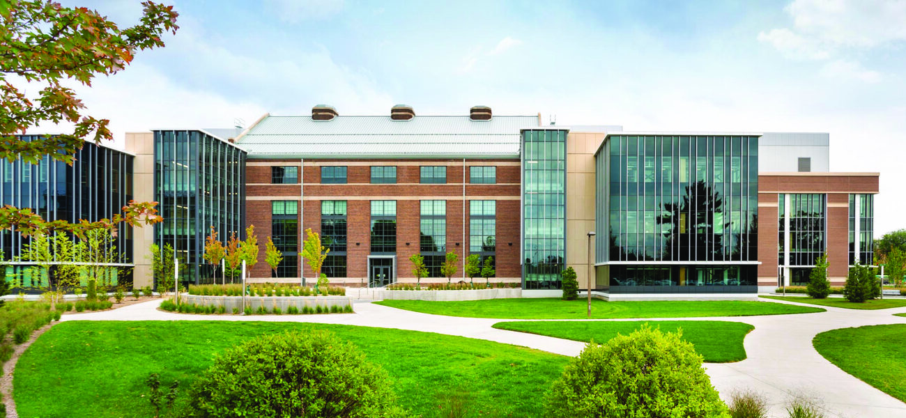 Building exterior with a glass facade on the left and the right with an older brick structure between them.