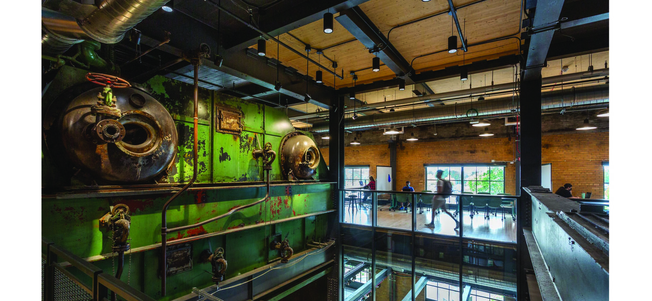 Old pieces of steel piping and other mechanical structures are displayed on a wall.
