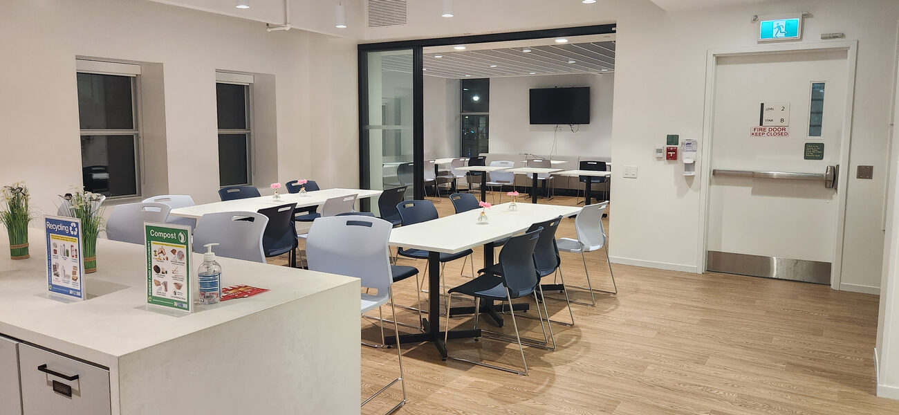 A large room with long tables and chairs, smaller tables with a single chair, and a counter with bar-height chairs.