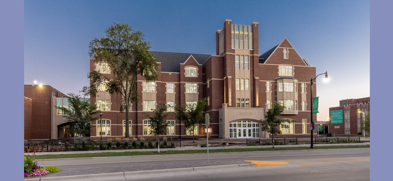 Front of a large brick building with a tower in the center.