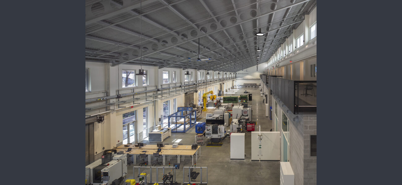A very long space with a very high ceiling is filled with work benches and equipment.