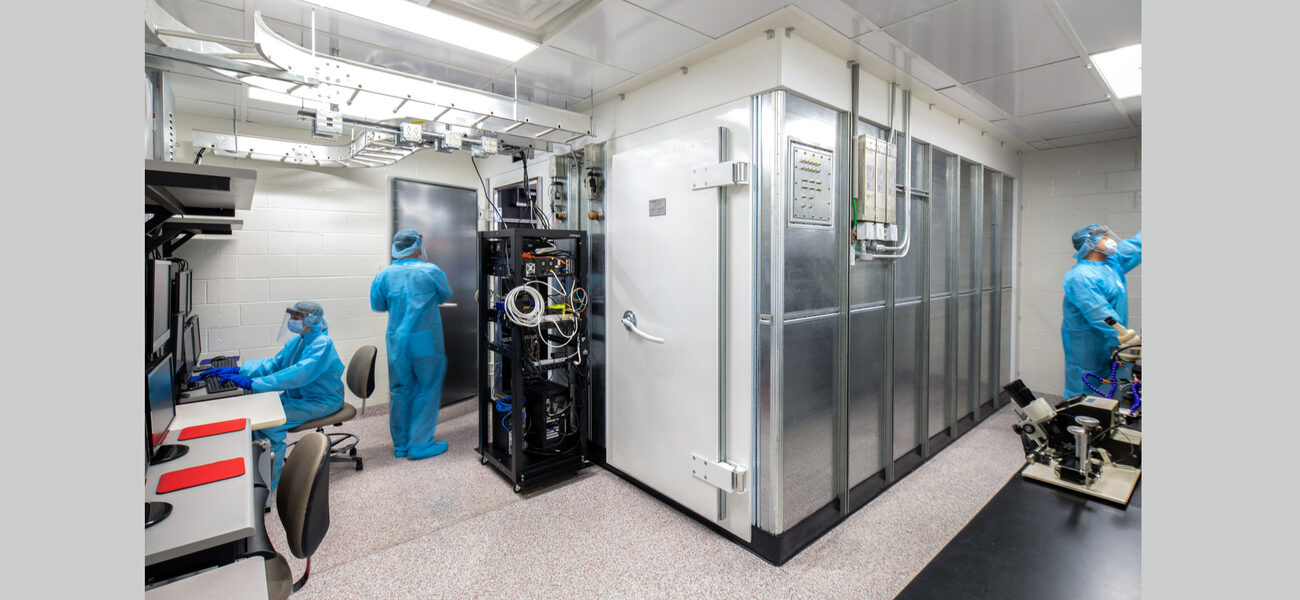 Two researchers wearing protectve gear work in a lab space