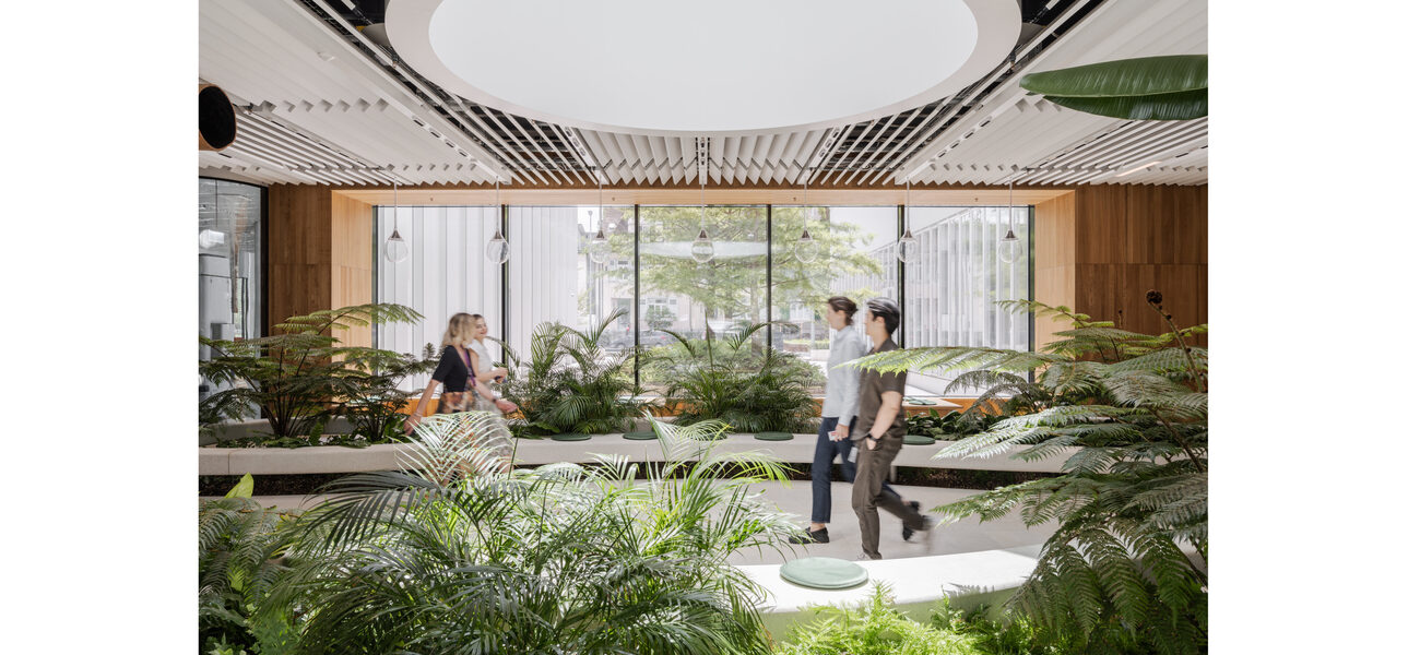 People walk through an interior walkway lined with plants