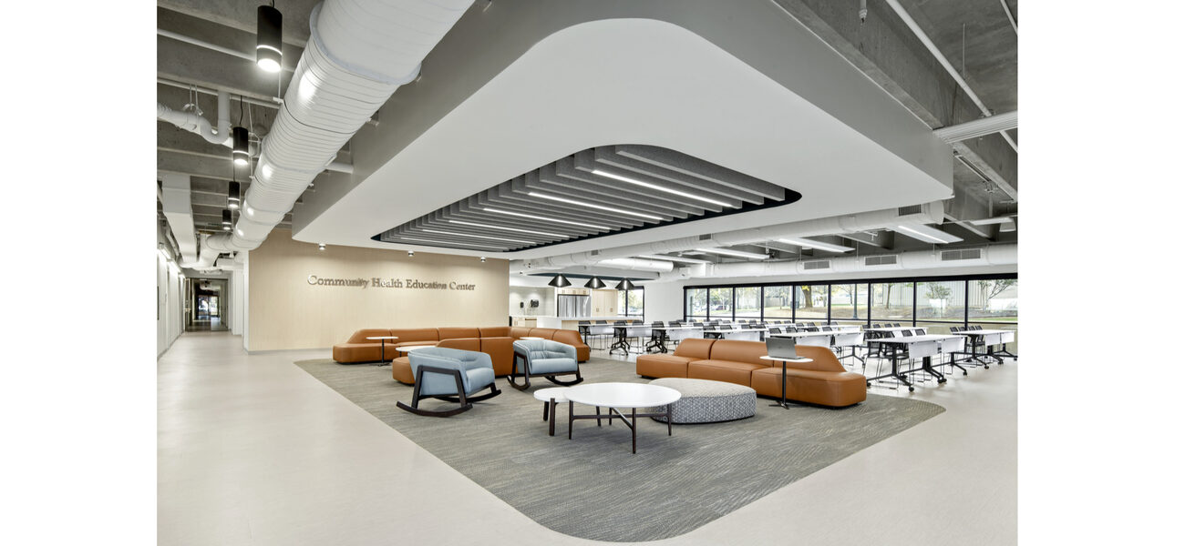Large open space filled with upholdtered rocking chairs and sofas around small tables, as well as long work tables and chairs
