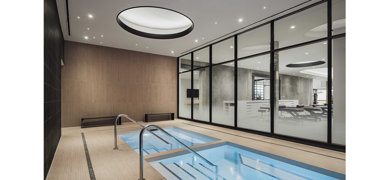 Two small pools, side-by-side, in front of a wal of windows.