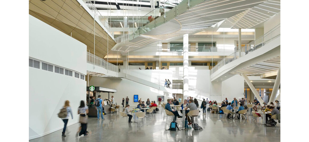 Large interior space with men and women sitting at small tables while others wander through