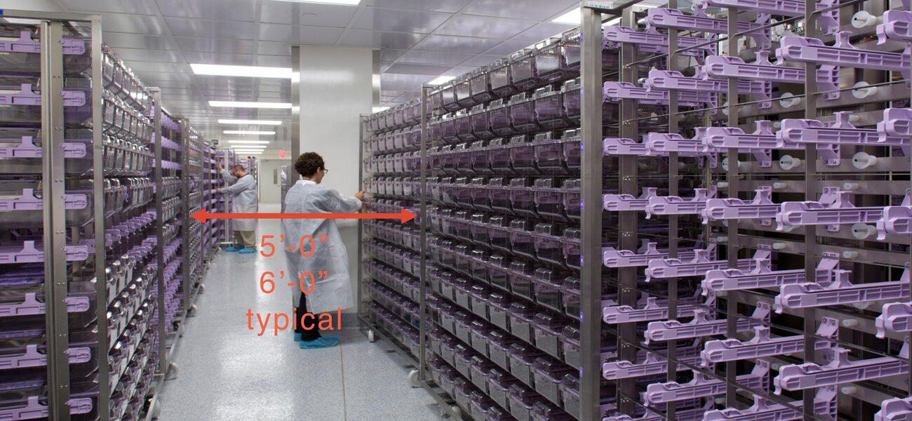 Two men in lab coats stand between ceiling-high racks of animal cages
