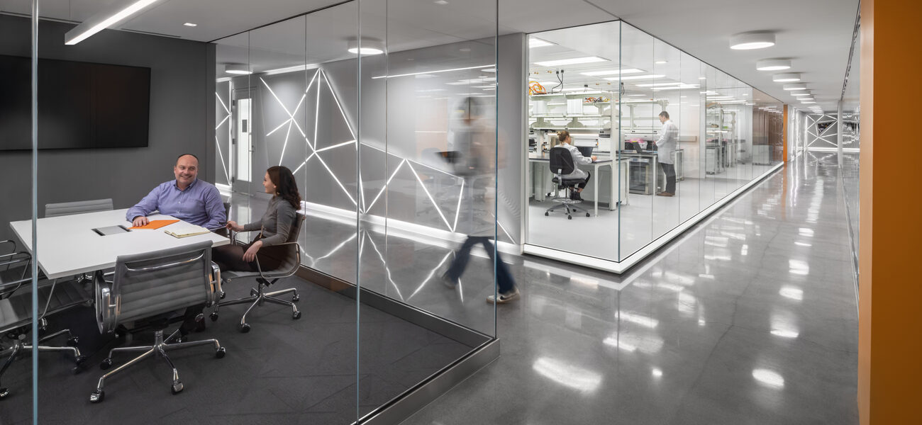 a long corridfor runs along a glass-fronted conference room and a lab.