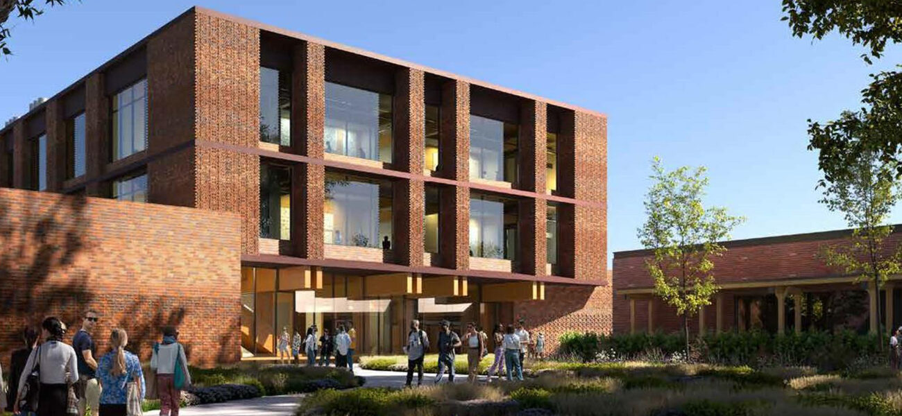 People walking towards and away from a large brick building 