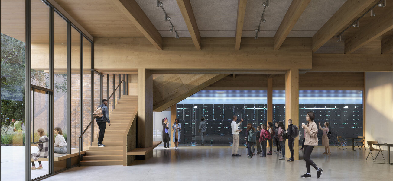 People milling around in a large open space with a wooden staircase next to a wall of floor-to-ceiling wondows.
