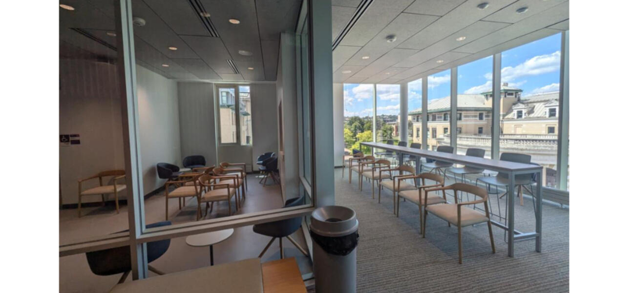 A longbar-height table sits in narrow space in a room lined with glass; behind it is a smaller glassed-in-room 