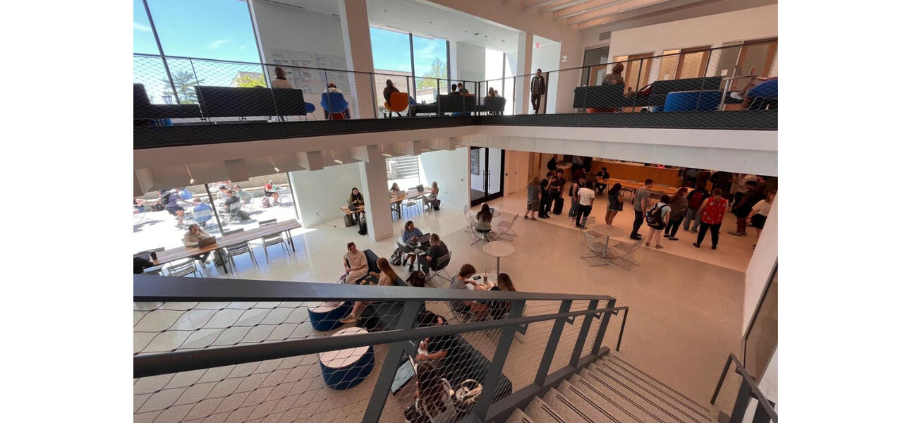 A staircase leads down into a lower level filled with young men and women.