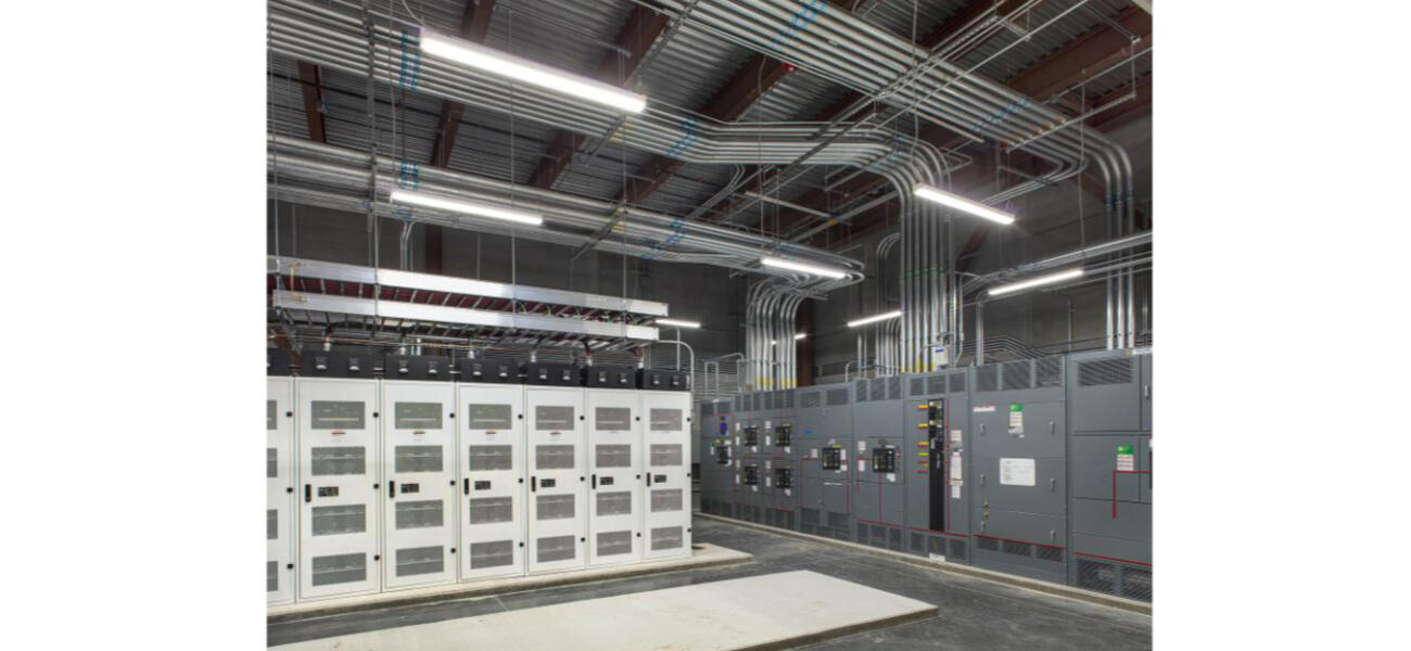A large room with banks of steel cabinets attached to many pipes that snake across the ceiling.