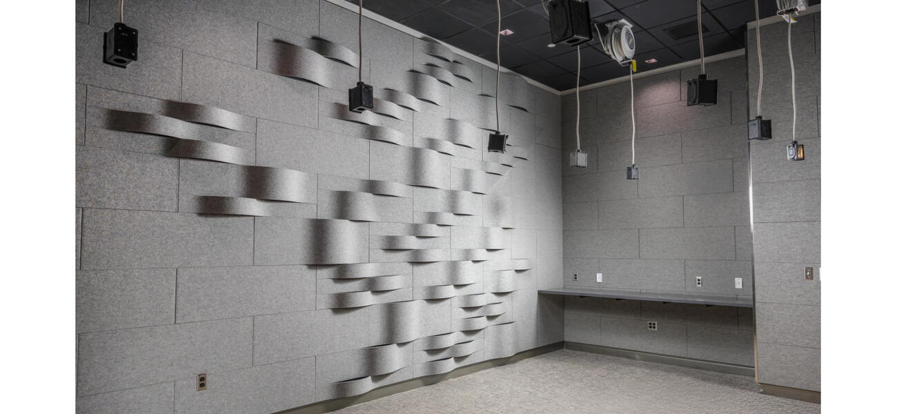 A room with walls lined with blocks, some of which are curved and protrude from the wall. Wired hang from the ceiling.
