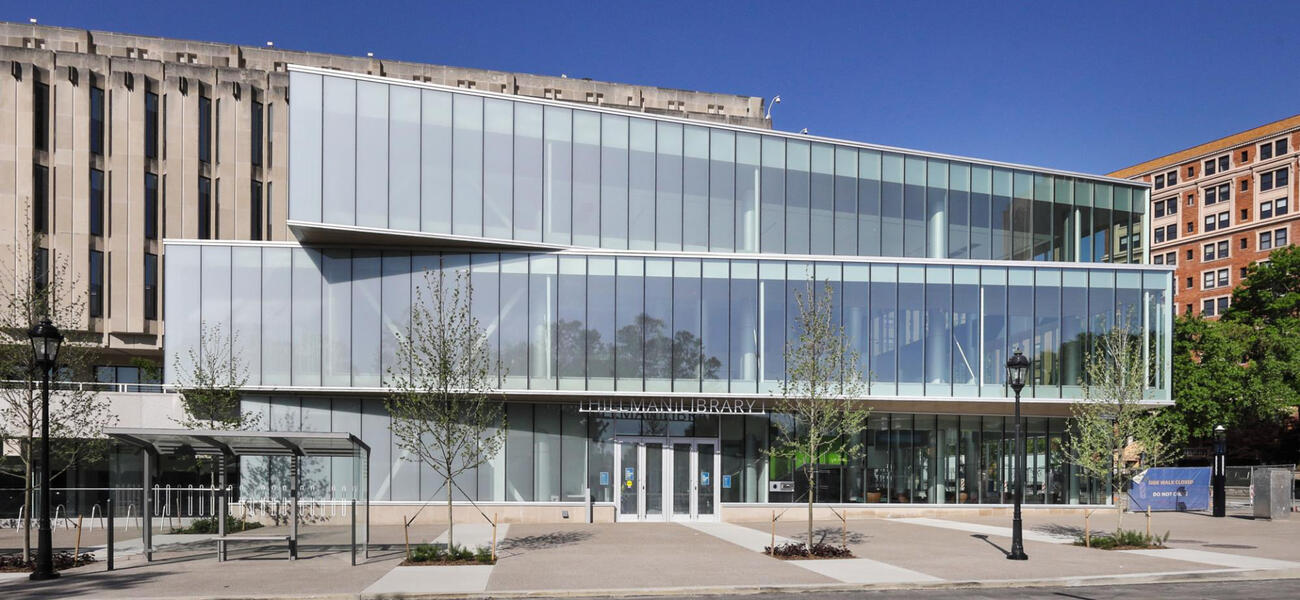 Large concrete building with an addition in front clad entirely in glass