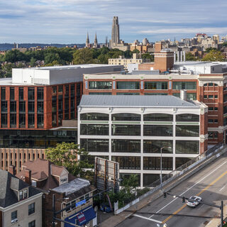 An indutrial-looking building with the Pittsburgh skyline behind it