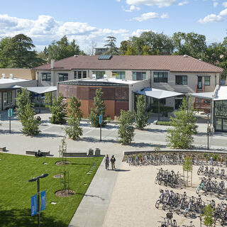 Building exterior with a plaza in front and several large bike racks full of bikes.
