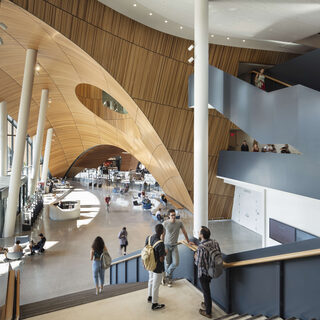 Students walk down a long staircase leading to a large open space.