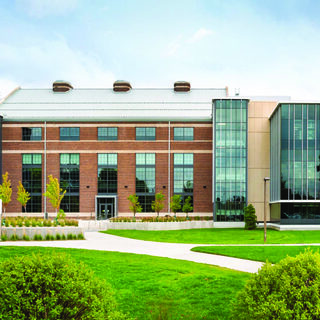 Building exterior with a glass facade on the left and the right with an older brick structure between them.