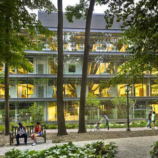 Exterior of a large building sheathed in glass with trees in the foreground