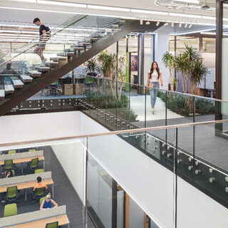 A man walks down a large staircase through a two-stpry atrium.