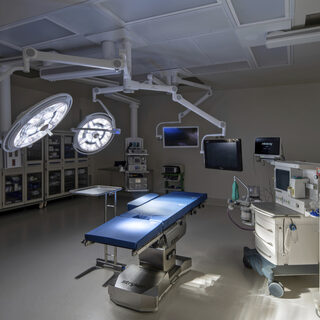 And operating table with bright lights above it and two computer monitors overhead.