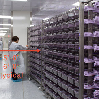 Two men in lab coats stand between ceiling-high racks of animal cages