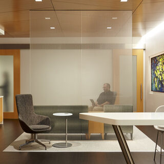 A man sits on a couch in a room that also has a coffee bar, a table and chairs.
