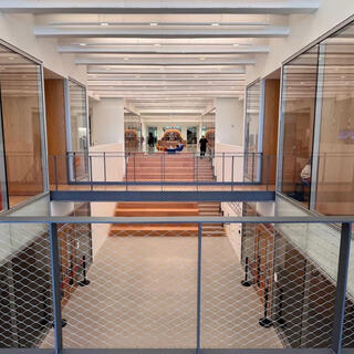 A wide corridor with two floors of room on either side, all sided in glass.