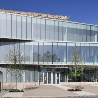 Large concrete building with an addition in front clad entirely in glass